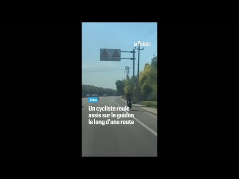 Chine : un cycliste roule assis sur son guidon dos à la route thumbnail